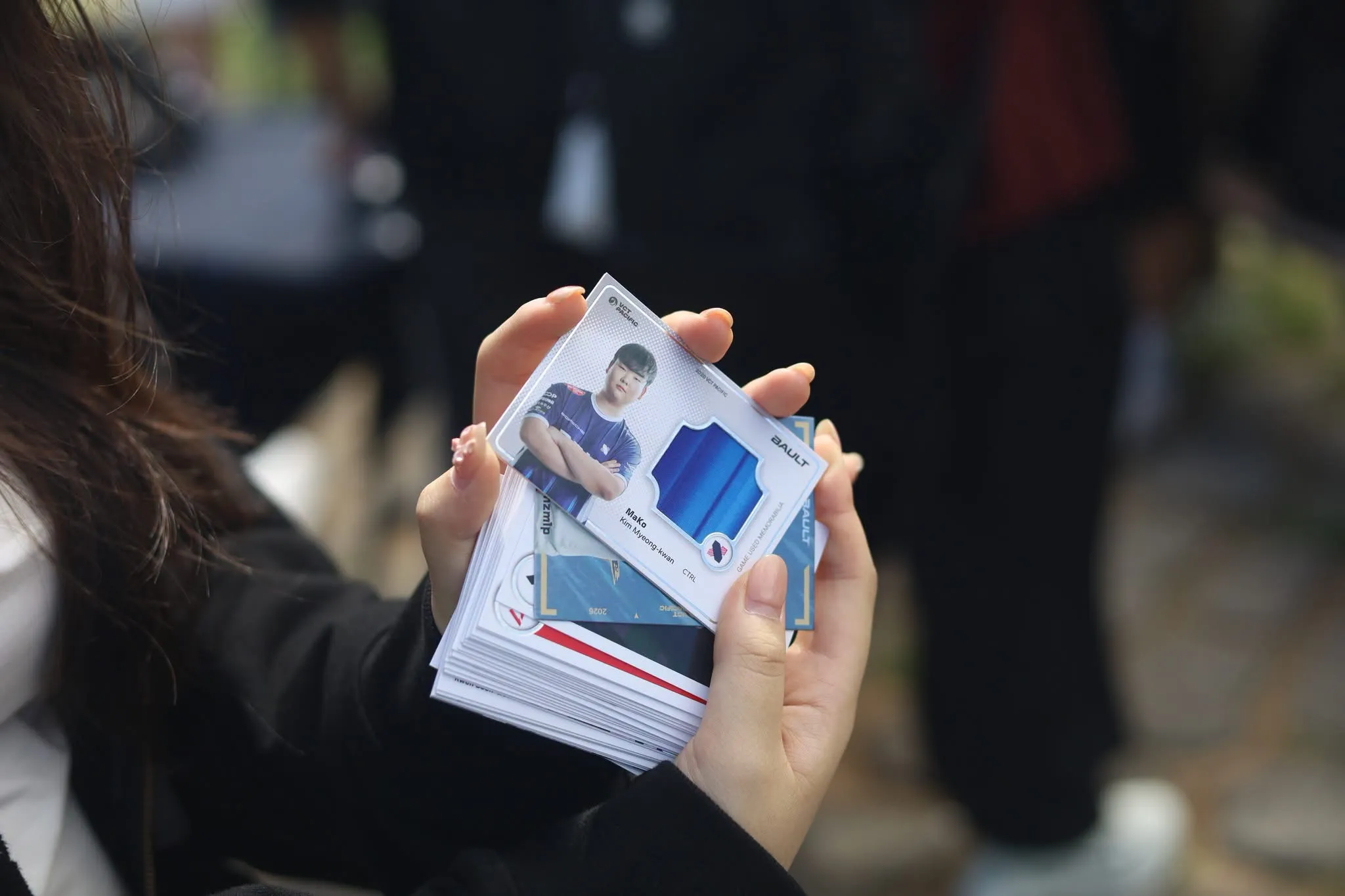 A fan holds a Mako player card from the Bault VCT Pacific series.